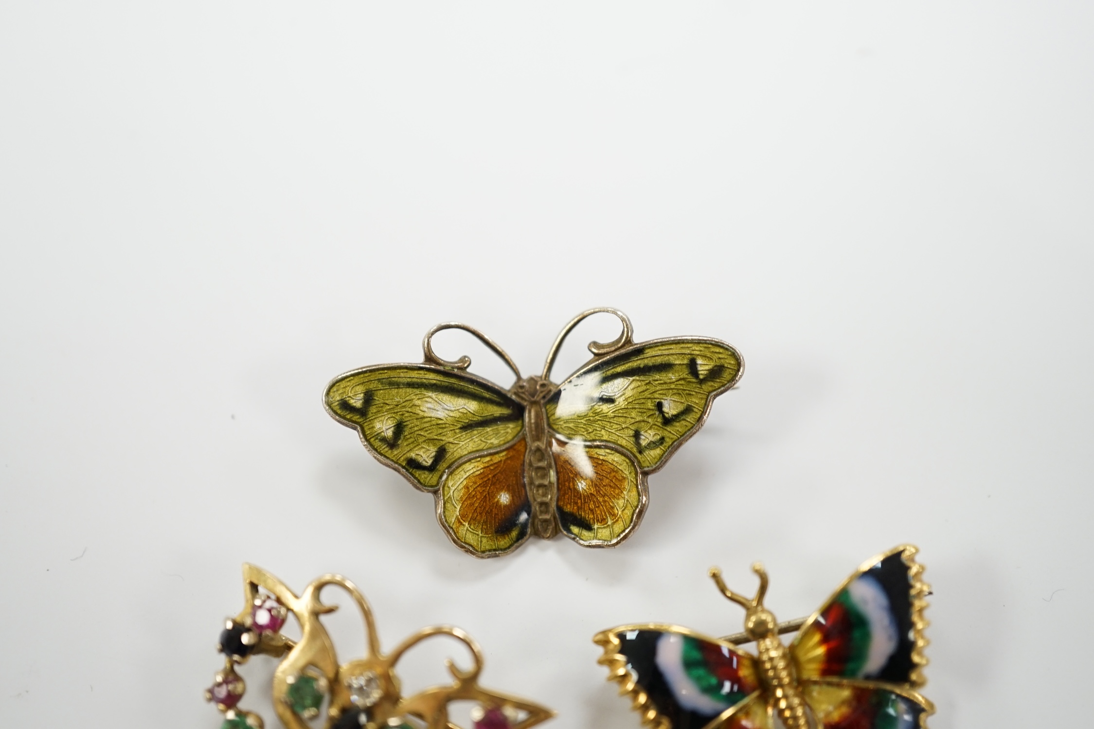 Three assorted butterfly brooches, sterling and enamel, 18k and enamel and 9ct gold and gem set, width 25mm.